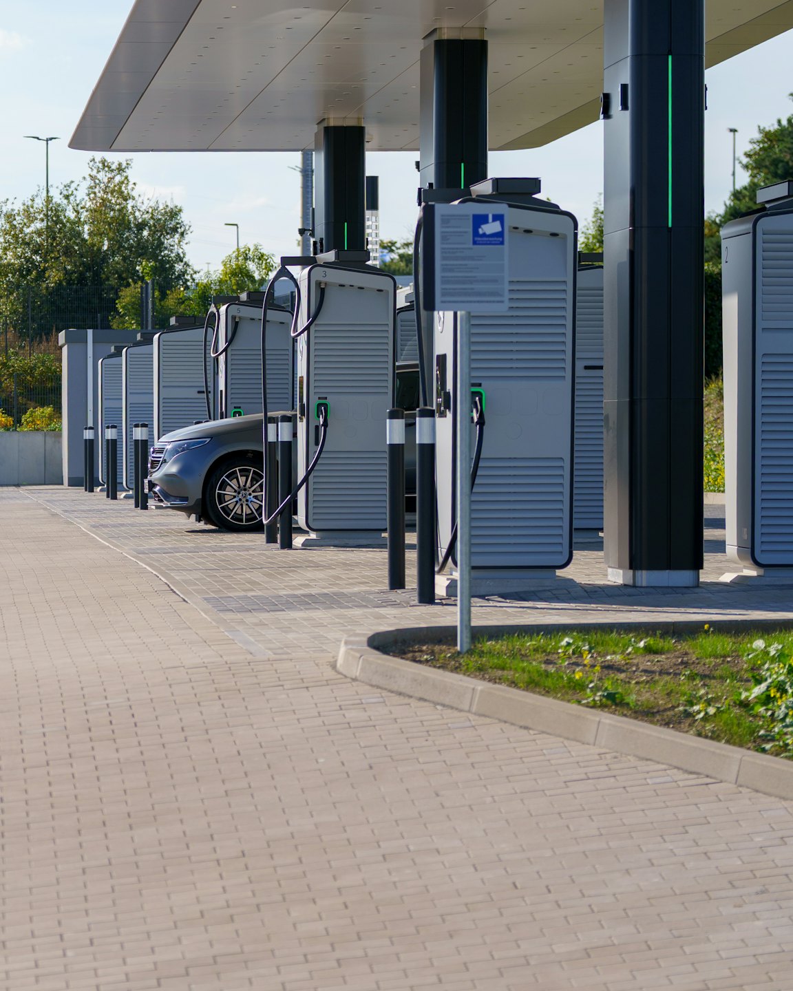 Ricarica di un veicolo elettrico presso una moderna stazione con tettoia.
